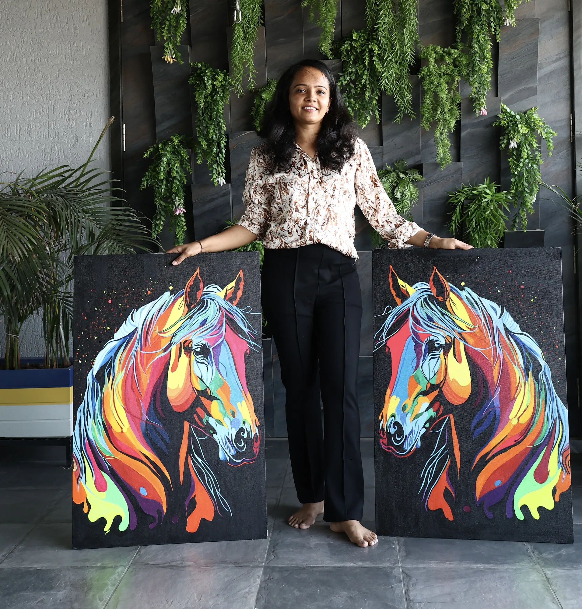 Darshana holding two of her horse paintings